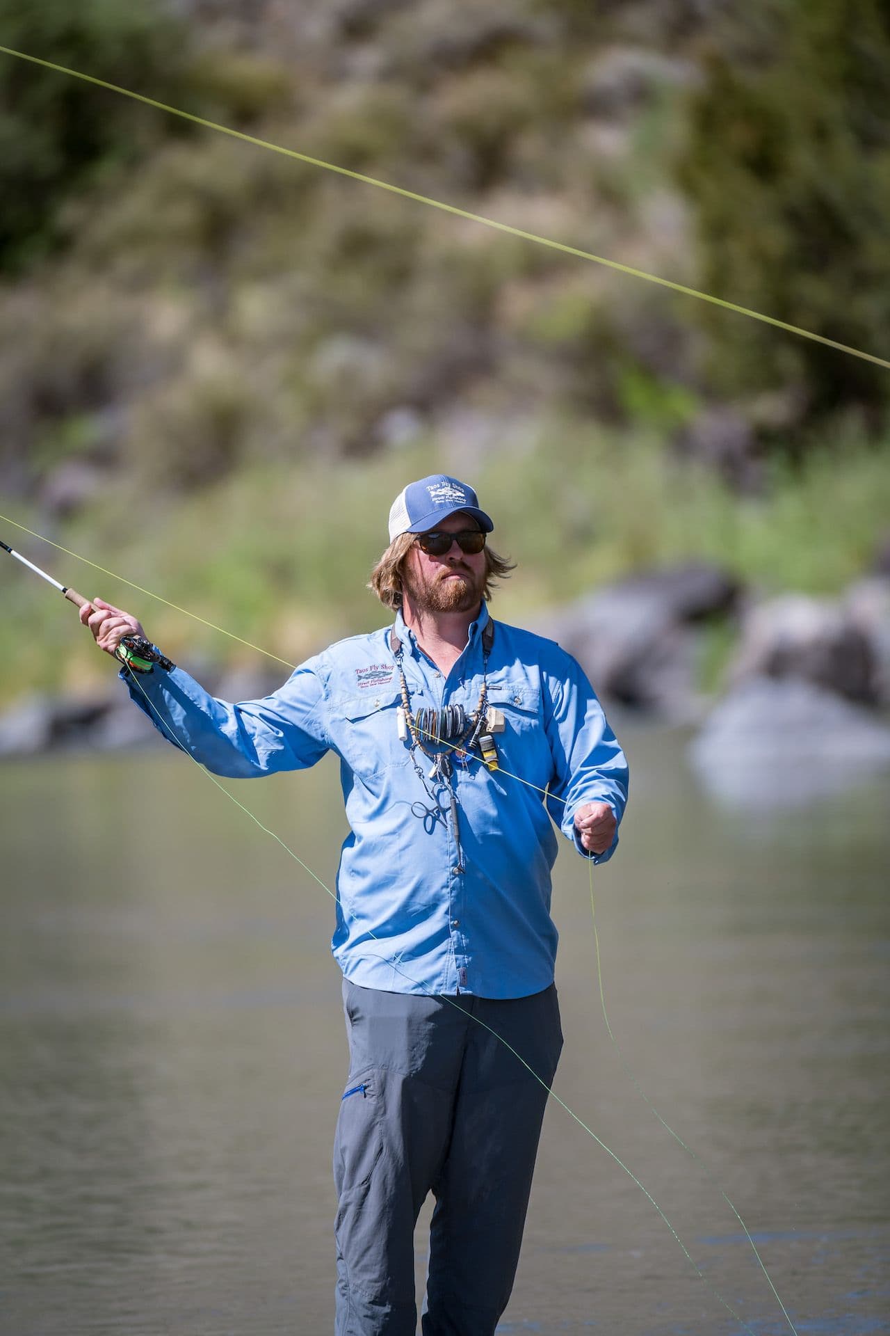 A person standing in a river and casting a fly rod.